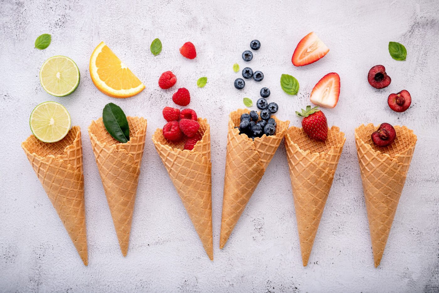 six ice cream cones with fruit