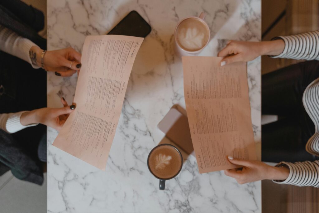 Two people sat at a marble topped table looking at restaurant menus